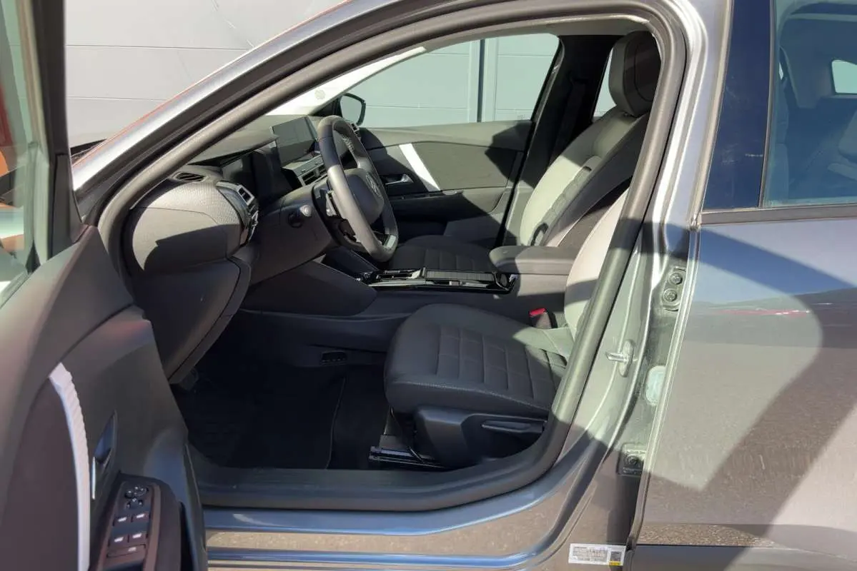 Intérieur de la Citroën C4 hybride gris mercury vu côté conducteur, montrant sièges et tableau de bord moderne.
