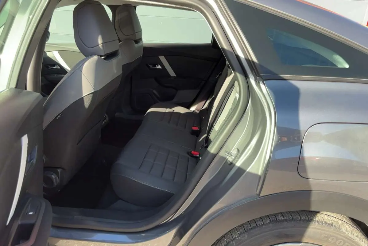 Vue intérieure côté gauche sur la banquette arrière et la portière ouverte d'une Citroën C4 hybride gris mercury.