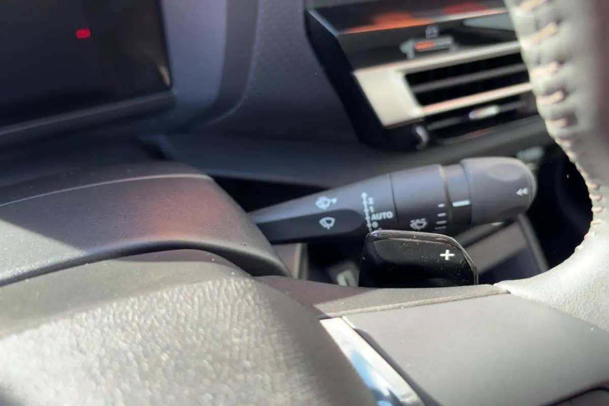 Détail intérieur du volant cuir de la Citroën C4 hybride 2025, avec palette de changement de vitesse et commande d’essuie-glace.