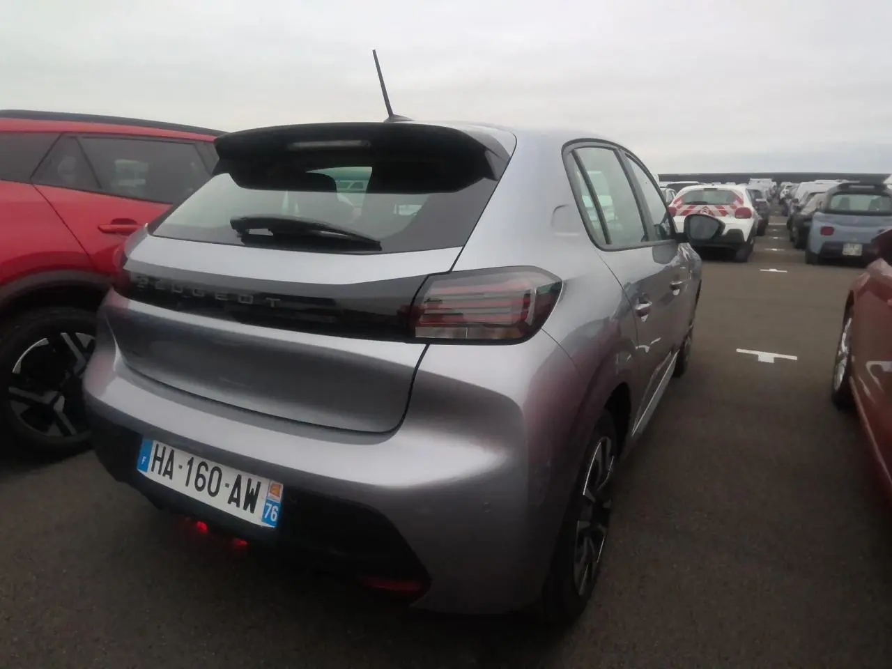 Vue 3/4 arrière droite d'une Peugeot 208 gris clair 2024, avec feux arrière fumés et toit noir contrastant.