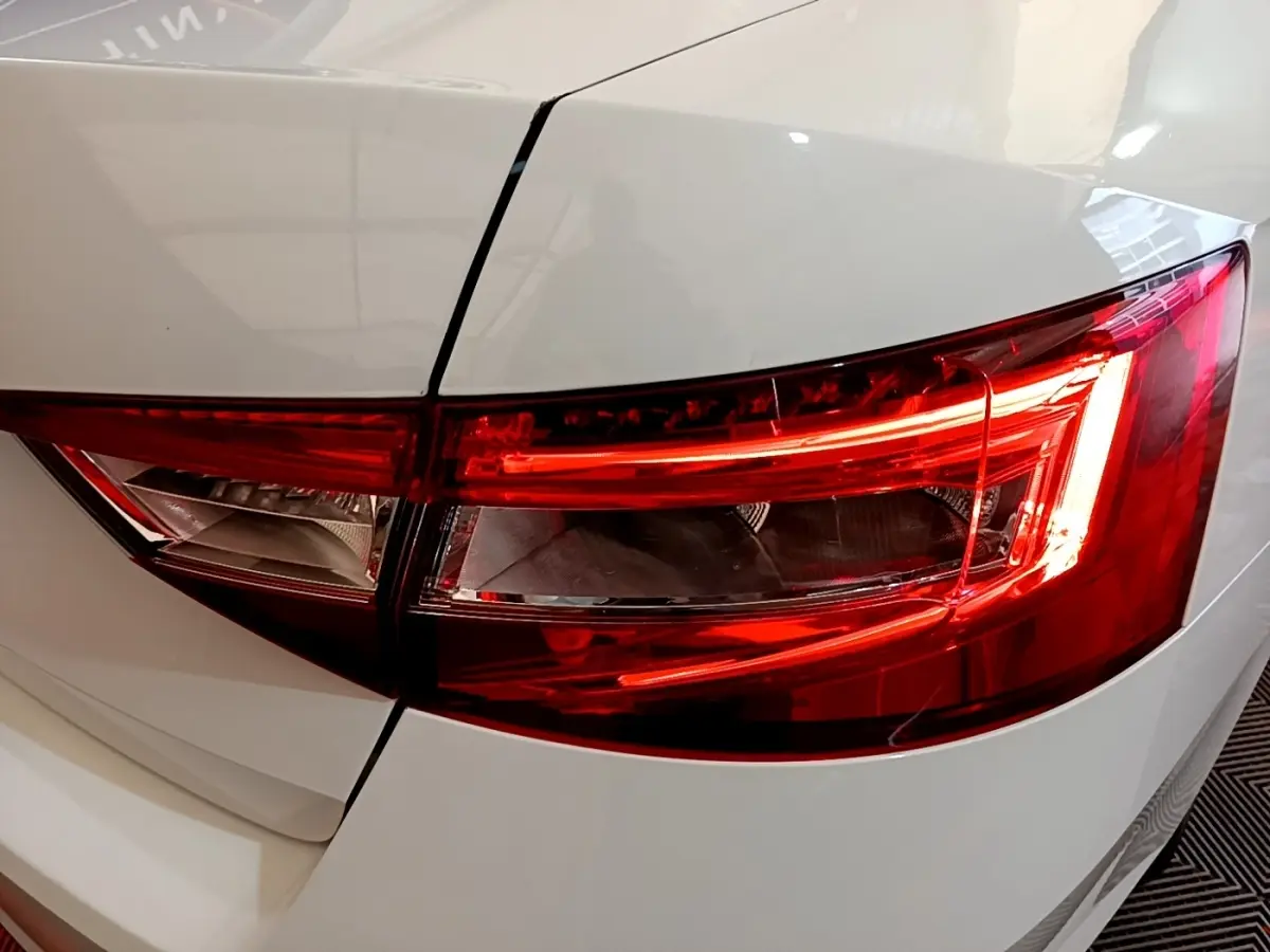 Gros plan sur le feu arrière droit rouge d’une Skoda Superb blanche, soulignant les lignes nettes du coffre.