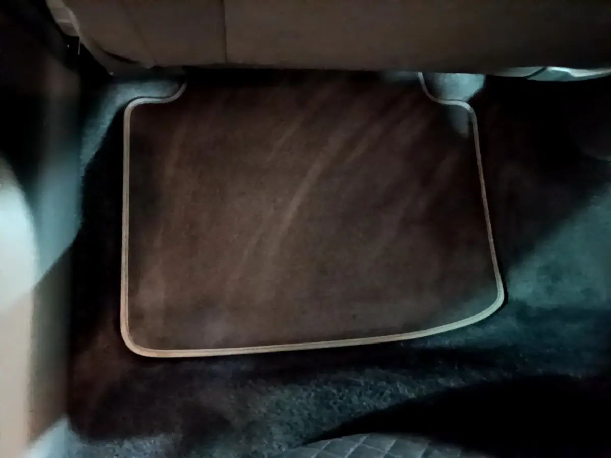 Tapis de sol noir avec bordure beige dans l'habitacle arrière d'une Skoda Superb blanche, vue du plancher arrière.