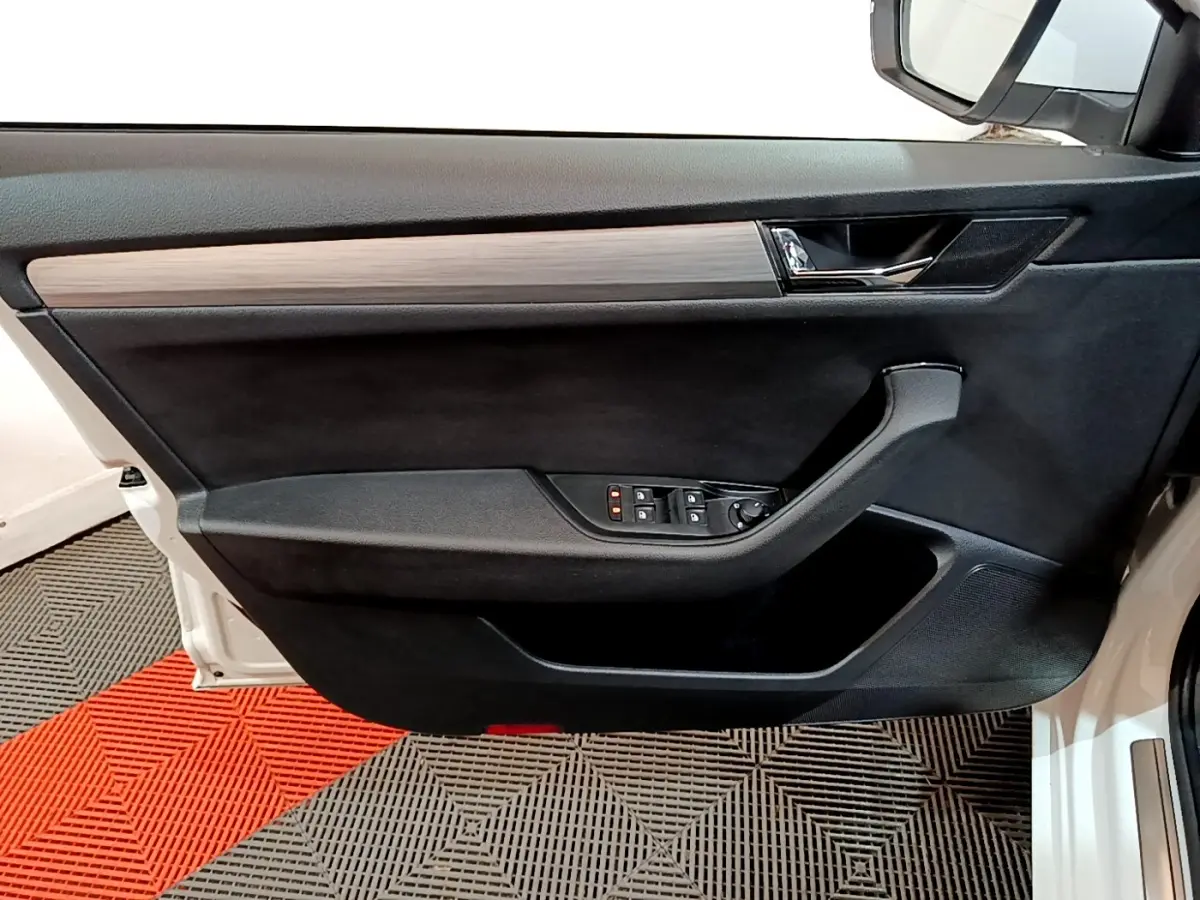 Vue intérieure côté gauche de la porte avant blanche d'une Skoda Superb 2021, avec garniture noire et insert bois.