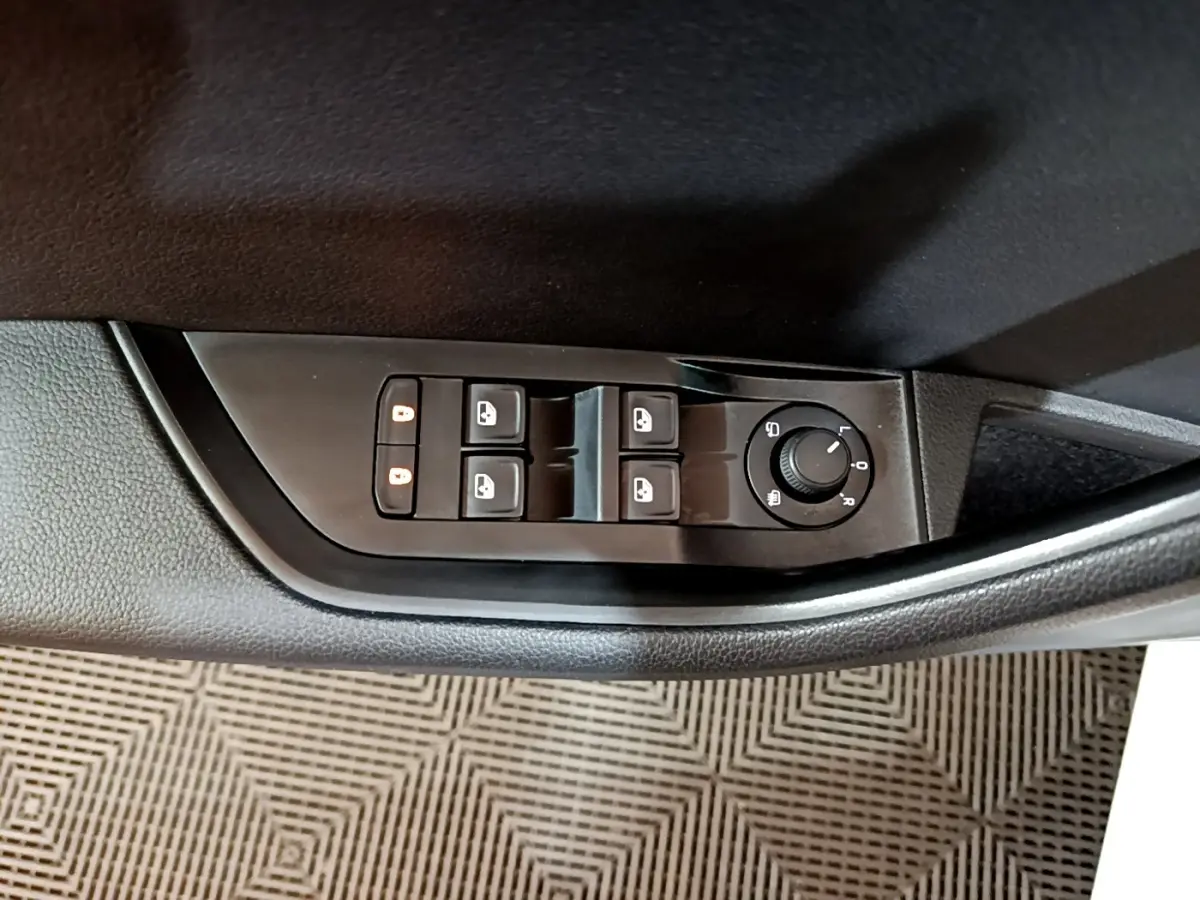 Vue rapprochée des commandes de lève-vitres et réglage des rétroviseurs côté conducteur d'une Skoda Superb blanche.