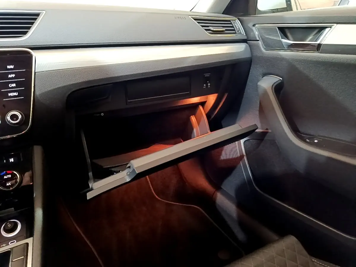 Intérieur de la Skoda Superb 2021, vue côté passager sur la boîte à gants ouverte avec éclairage intérieur orange.