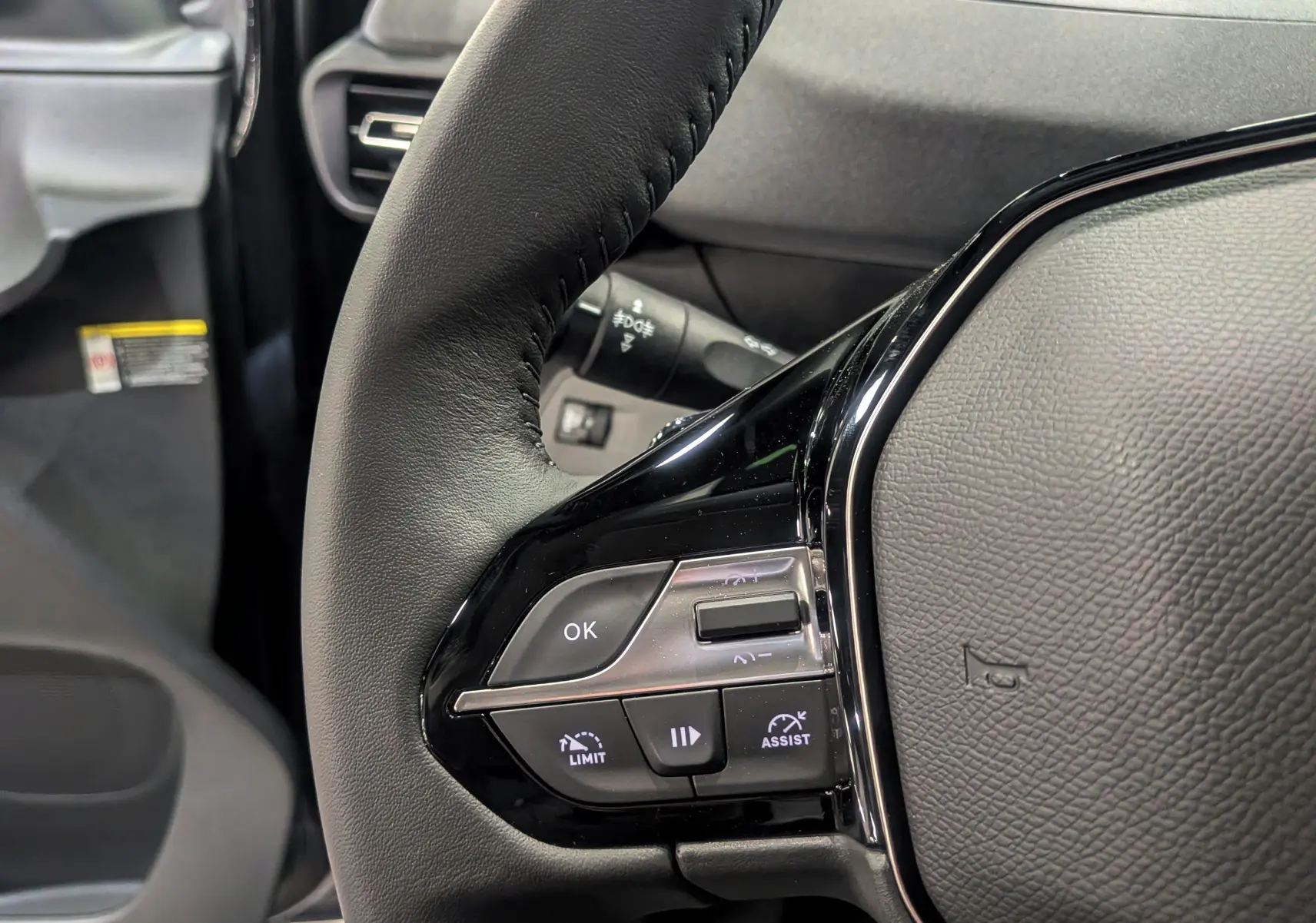 Gros plan sur le volant cuir noir du Peugeot Rifter 2025, mettant en valeur les commandes intégrées côté gauche.