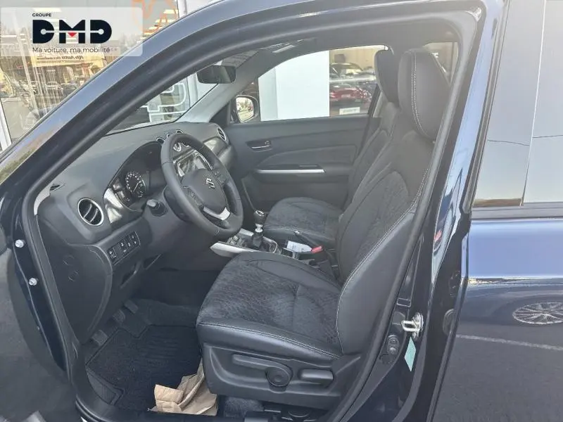 Intérieur côté conducteur du Suzuki Vitara bleu, montrant sièges en suédine et cuir noir avec volant multifonction.
