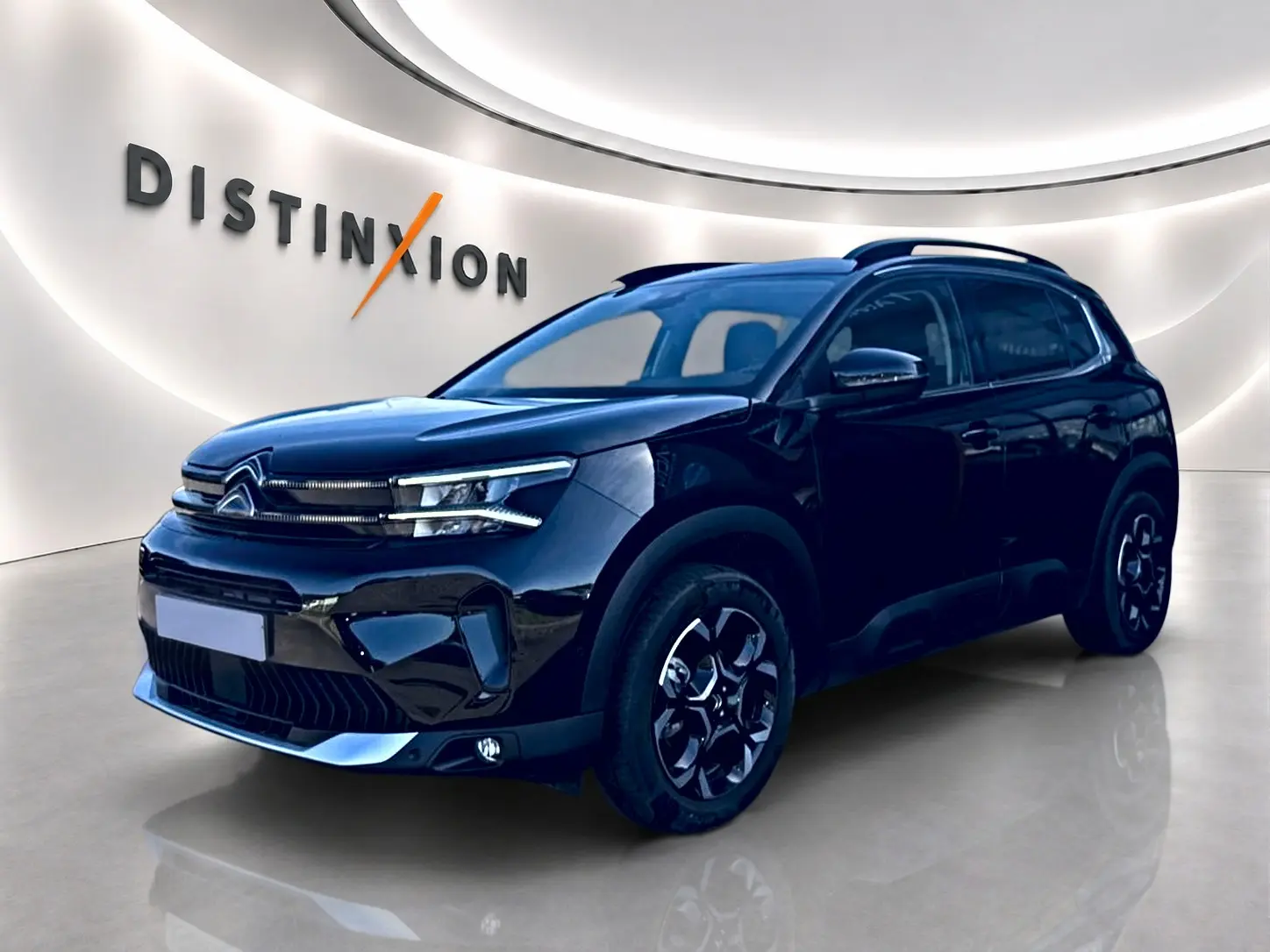 Citroën C5 Aircross noir vue 3/4 avant droit avec jantes alu et barres de toit en showroom lumineux.