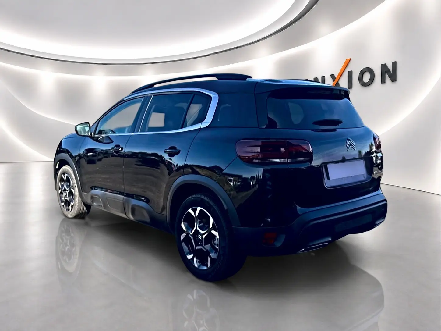 Citroën C5 Aircross noir vue 3/4 arrière droit, jantes alu et barres de toit visibles dans un studio lumineux.