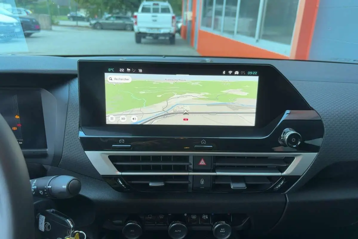 Vue intérieure du tableau de bord de la Citroën C4 hybride 2025 avec écran tactile de navigation et commandes de climatisation.