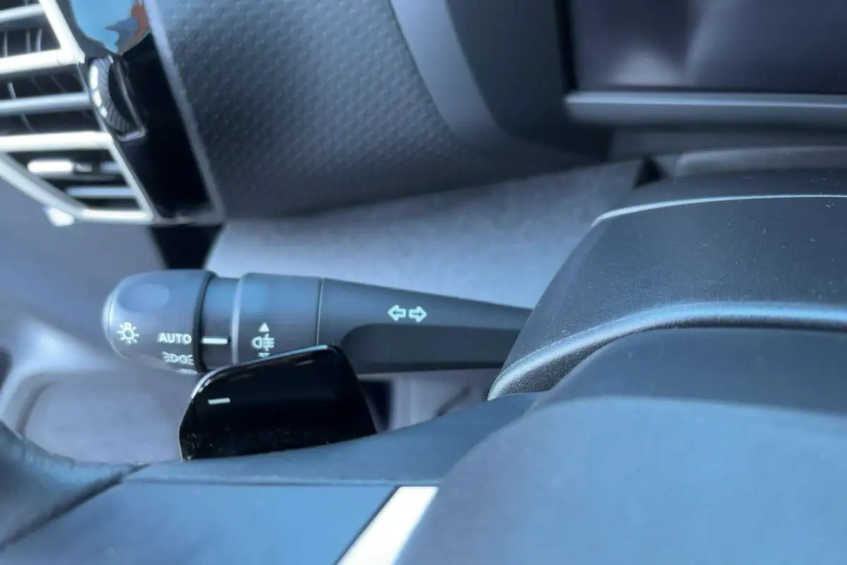 Gros plan sur la commande des feux et clignotants côté gauche du volant cuir du Citroën C4 hybride 2025.