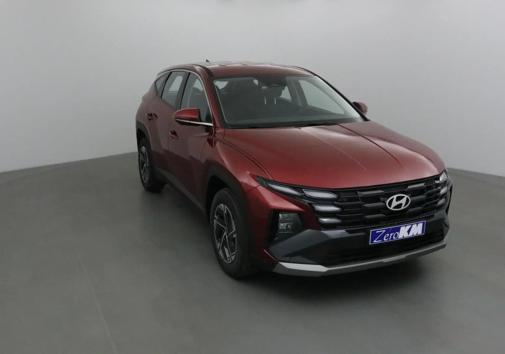 Vue 3/4 avant gauche du Hyundai Tucson 2025 rouge Ultimate avec calandre noire et jantes alliage 17 pouces.