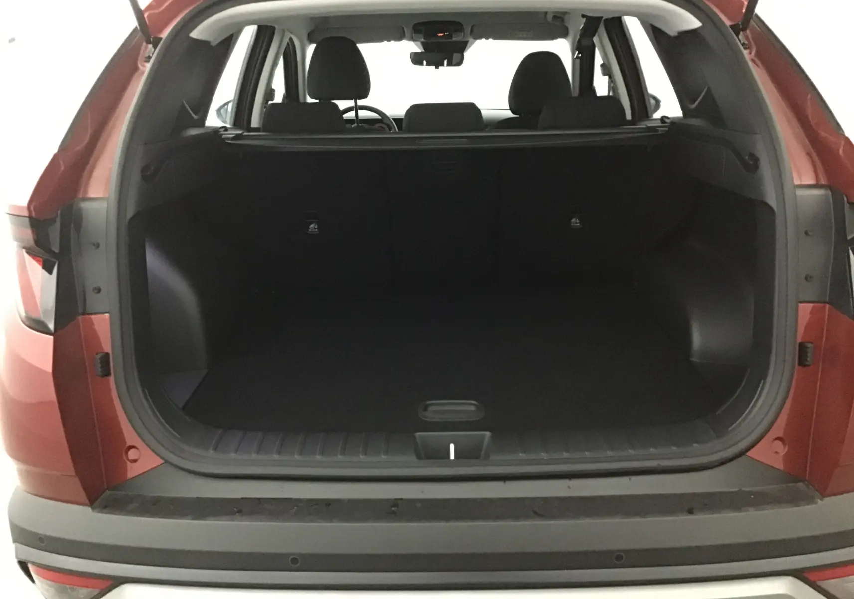 Coffre ouvert d'un Hyundai Tucson 2025 rouge Ultimate vu de l'arrière, montrant l'espace de chargement vide et l'intérieur noir.