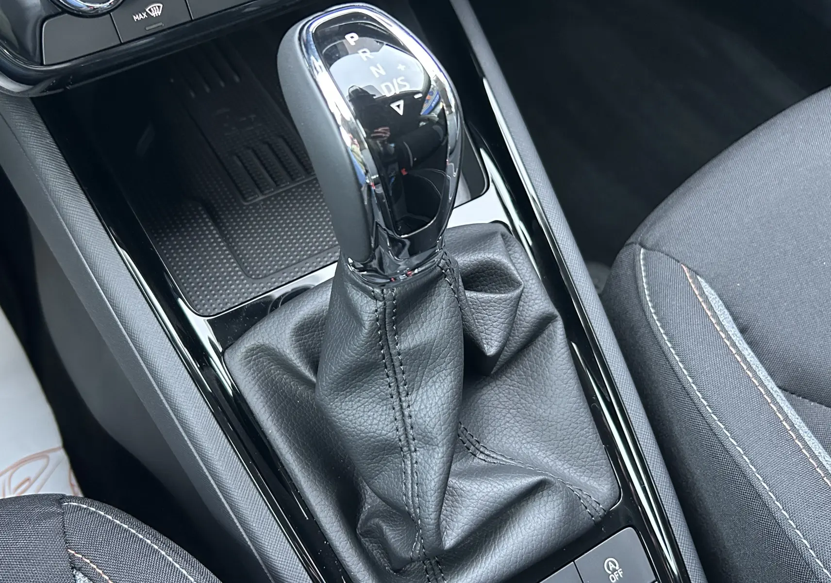 Gros plan sur la commande de boîte automatique cuir noir du Skoda Kamiq 2025, intérieur tissu gris avec surpiqûres contrastées.