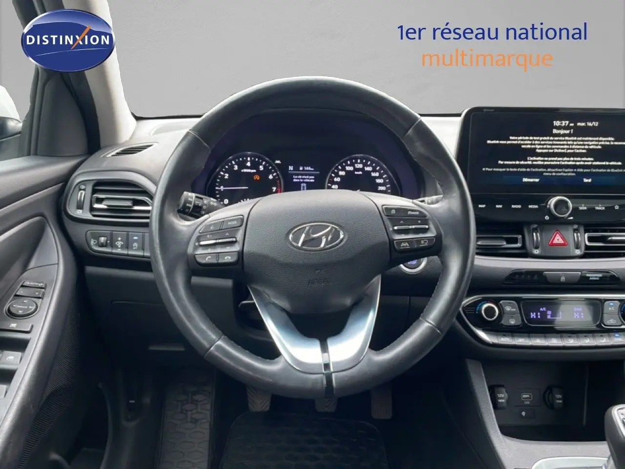 Vue intérieure centrée sur le volant cuir noir et le tableau de bord digital de la Hyundai i30 SW 2023.