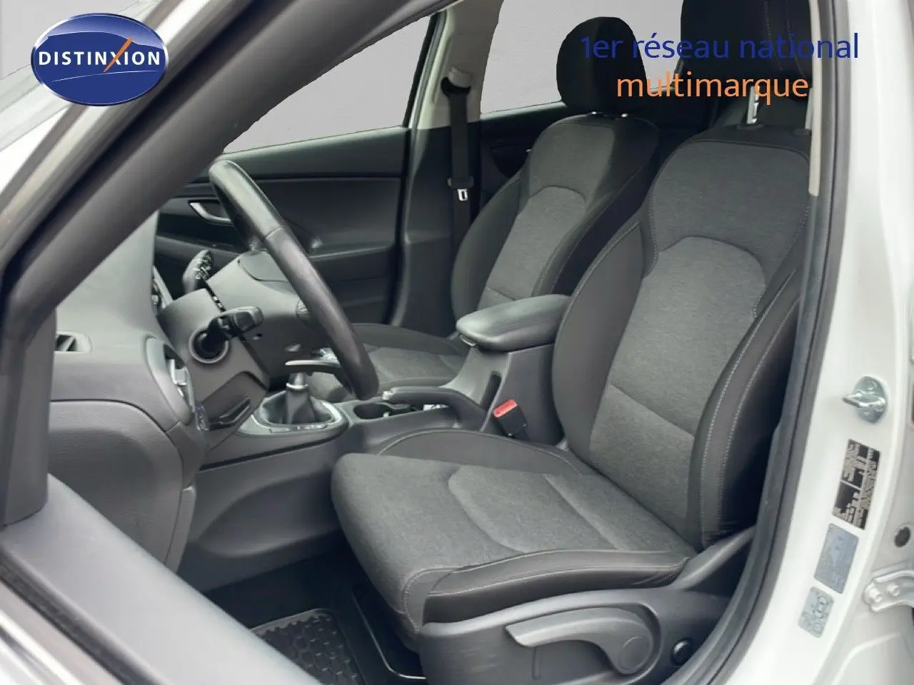 Intérieur côté conducteur de la Hyundai i30 SW blanc Atlas 2023, sièges tissu gris et volant cuir noir.