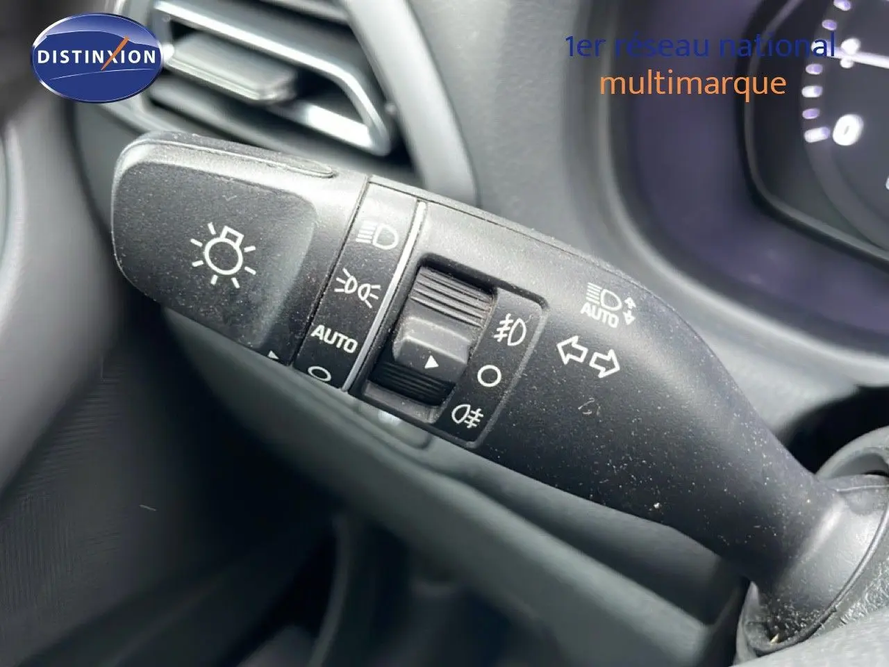 Gros plan sur la commande des feux et clignotants à gauche du volant dans l'habitacle d'une Hyundai i30 SW blanche.