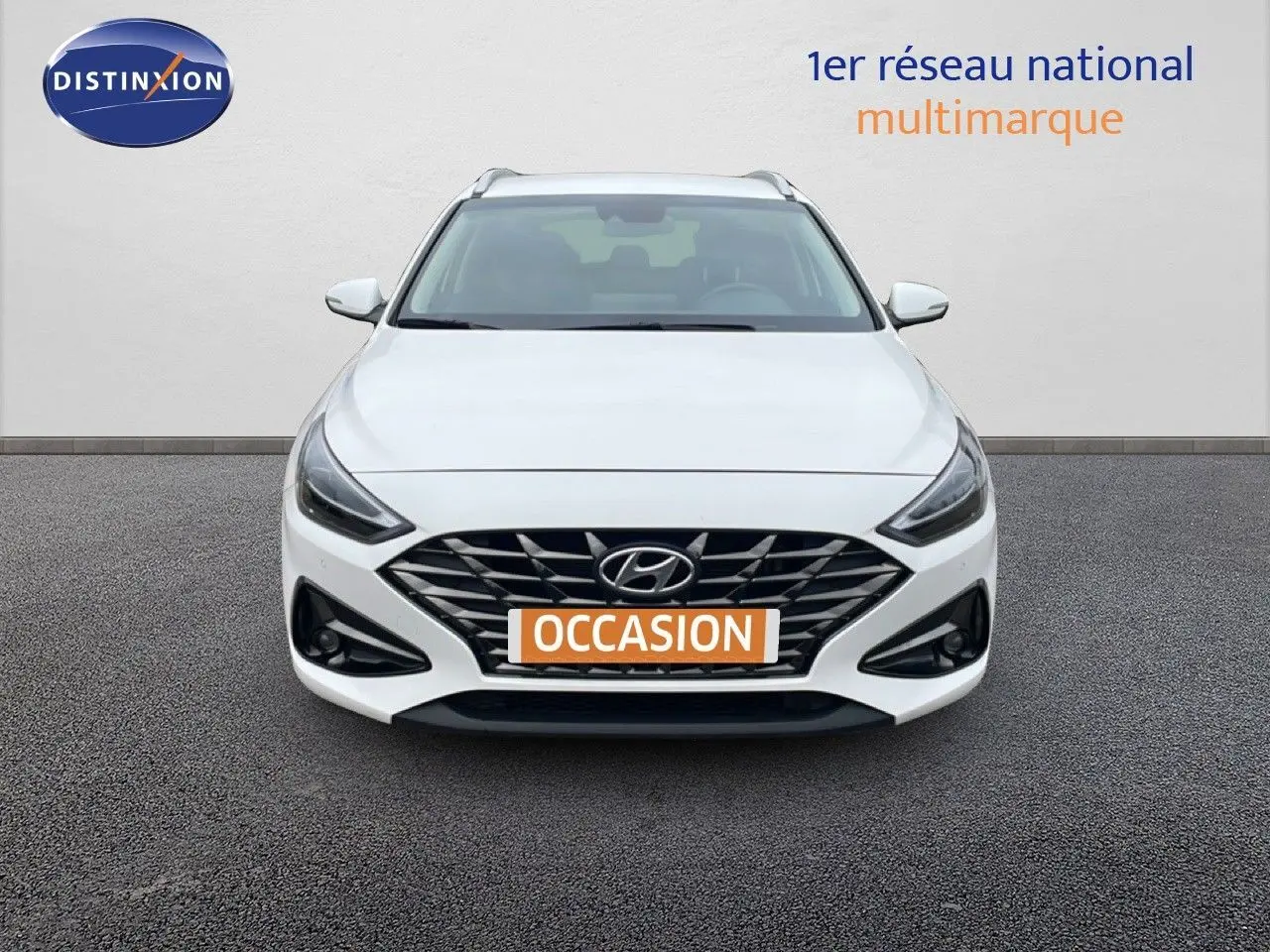 Vue frontale d'une Hyundai i30 SW 1.5 T-GDI 160CH FAMILY SMART blanche avec calandre noire et feux LED.