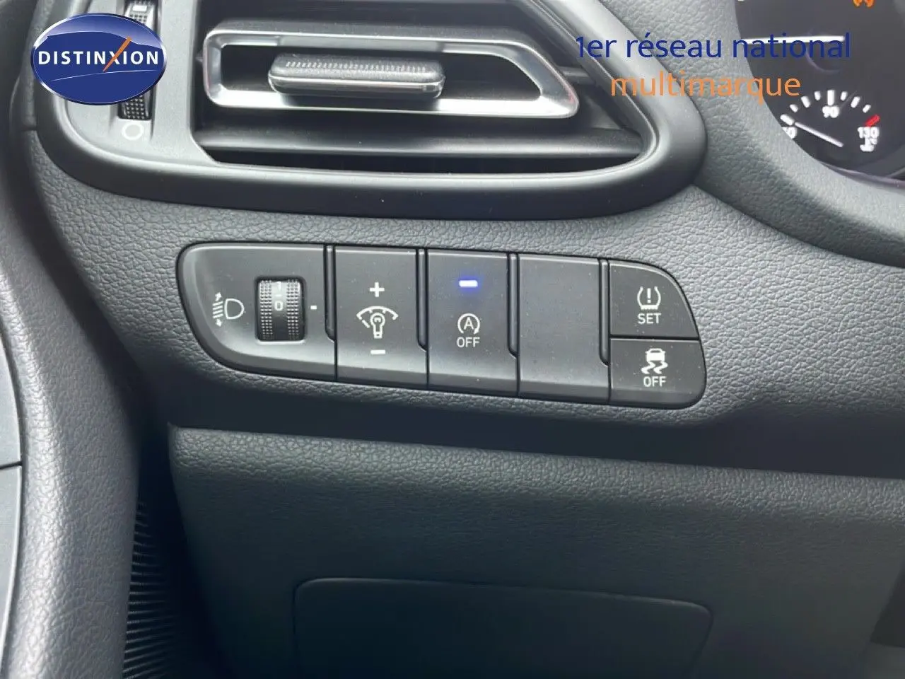 Détail du tableau de bord côté gauche avec commandes d'éclairage et aides à la conduite sur Hyundai i30 SW blanc.