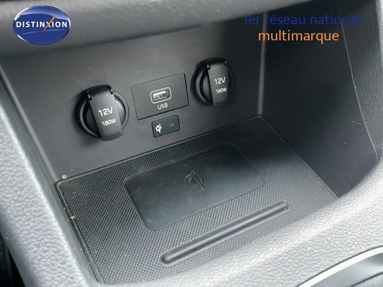 Détail de la console centrale de la Hyundai i30 SW 2023 montrant prises 12V, port USB et zone de recharge sans fil.