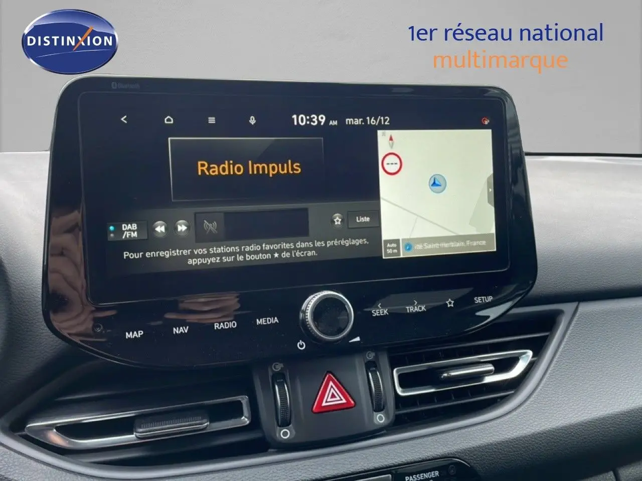 Tableau de bord de Hyundai i30 SW 2023 avec écran tactile central affichant radio et navigation, ambiance intérieure moderne.
