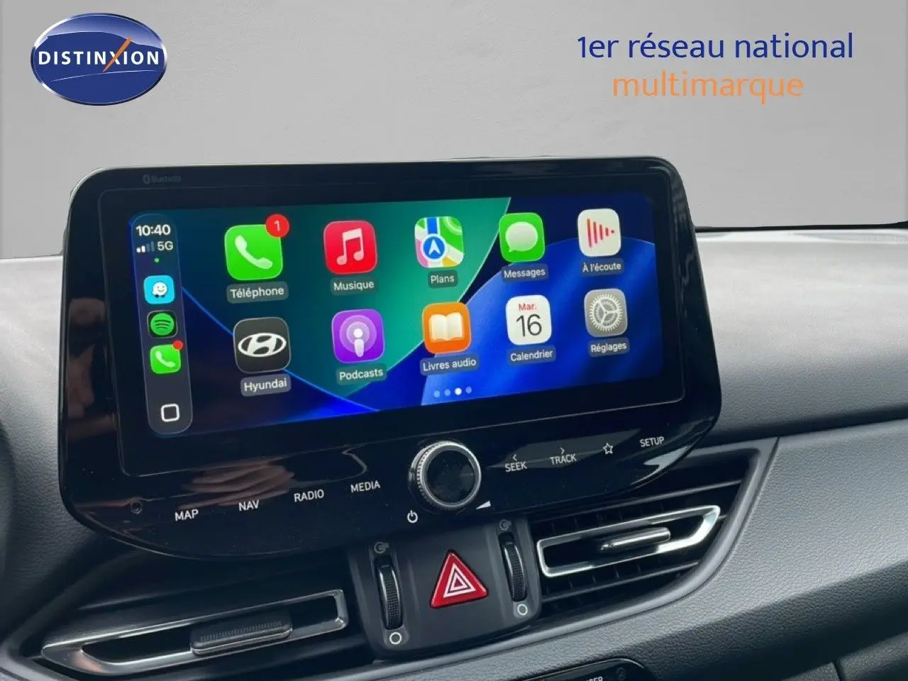 Écran tactile central affichant Apple CarPlay dans l’habitacle d’une Hyundai i30 SW blanche, vue de face.