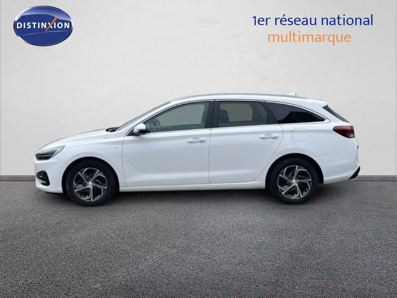 Profil latéral droit d'une Hyundai i30 SW 2023 blanche Atlas, break compact avec jantes alliage et vitres teintées.