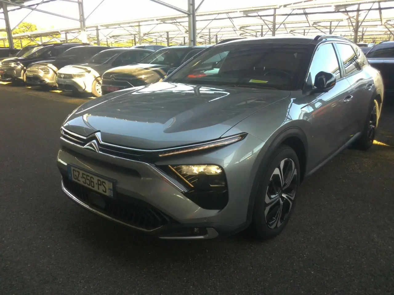 Citroën C5 X gris foncé vue 3/4 avant droit avec feux allumés et calandre distinctive, année 2024.