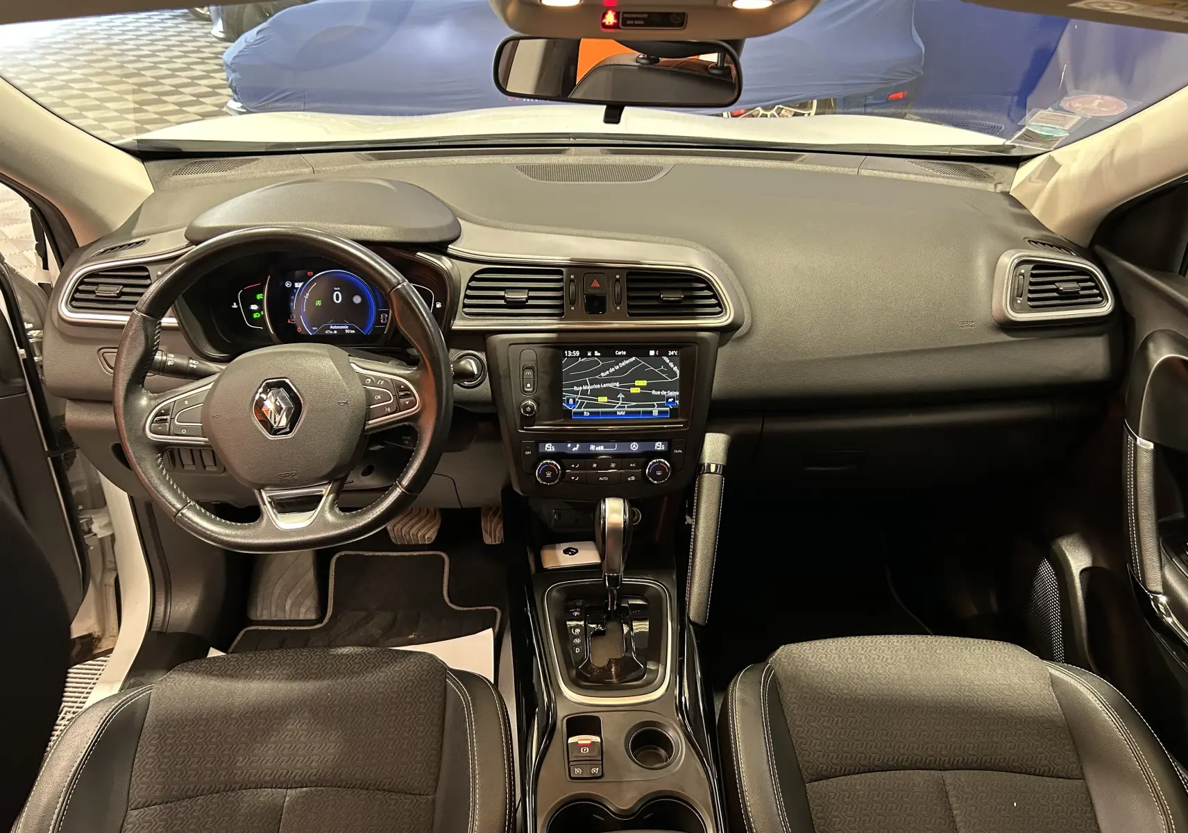 Vue intérieure avant du Renault Kadjar blanc 2018, tableau de bord avec écran tactile et volant cuir à droite ouverte.