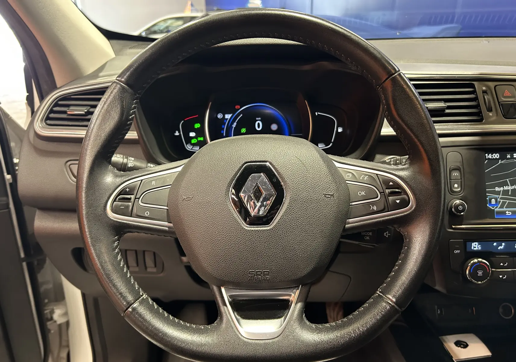 Vue rapprochée du volant en cuir noir du Renault Kadjar blanc 2018 avec tableau de bord digital et écran central tactile.