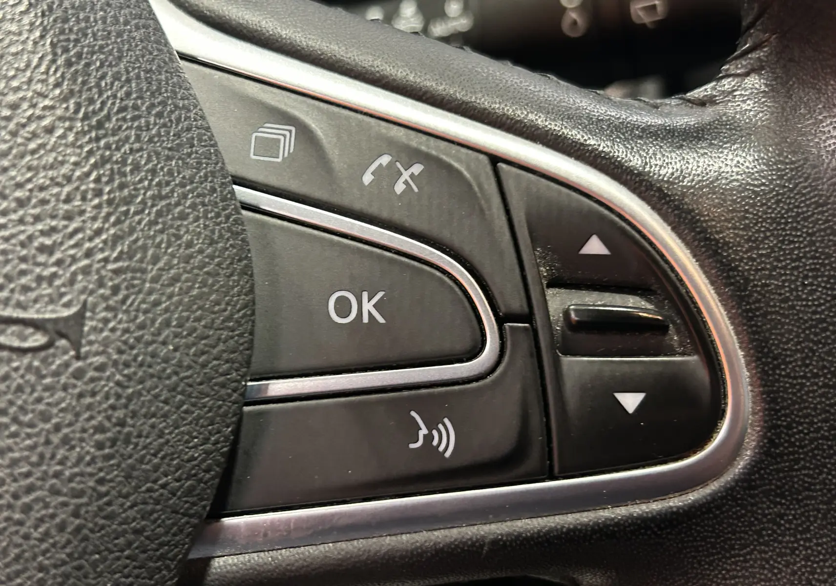 Gros plan sur les commandes multifonctions noires du volant en cuir d’un Renault Kadjar blanc de 2018.