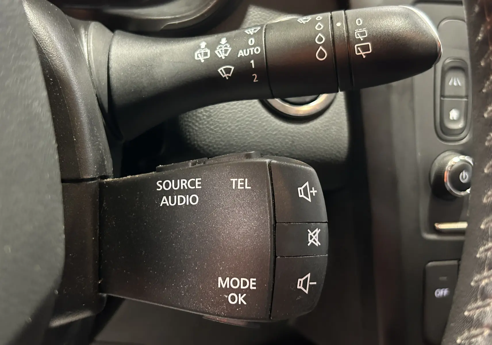 Gros plan sur les commandes audio et essuie-glace à gauche du volant dans un Renault Kadjar blanc de 2018.