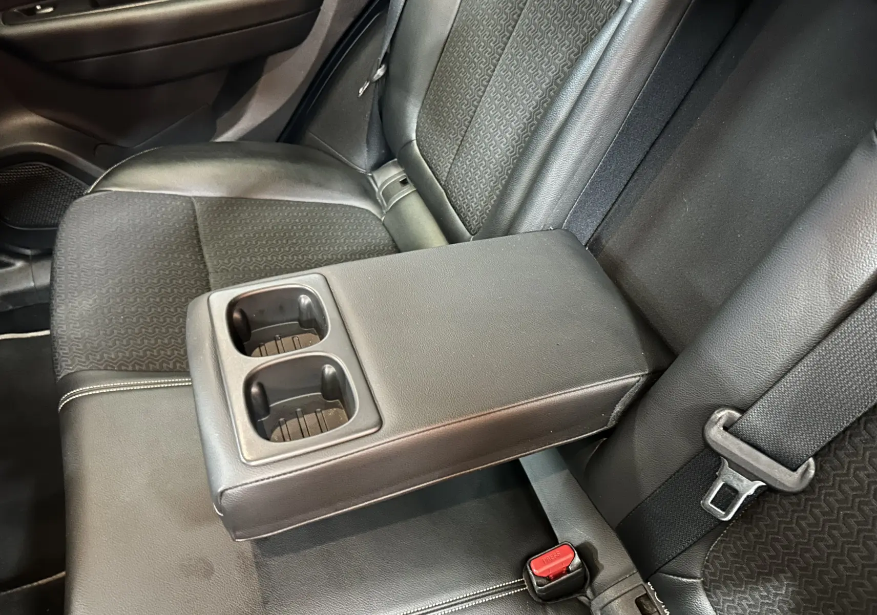 Détail de l'accoudoir central arrière avec porte-gobelets dans l'habitacle noir du Renault Kadjar blanc.
