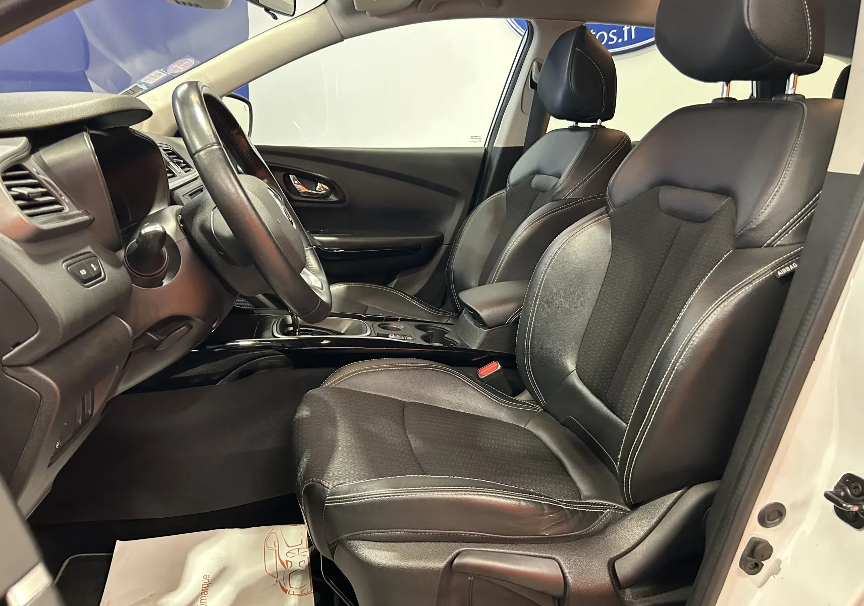 Vue intérieure côté conducteur du Renault Kadjar blanc 2018, sièges cuir noirs et tableau de bord moderne.