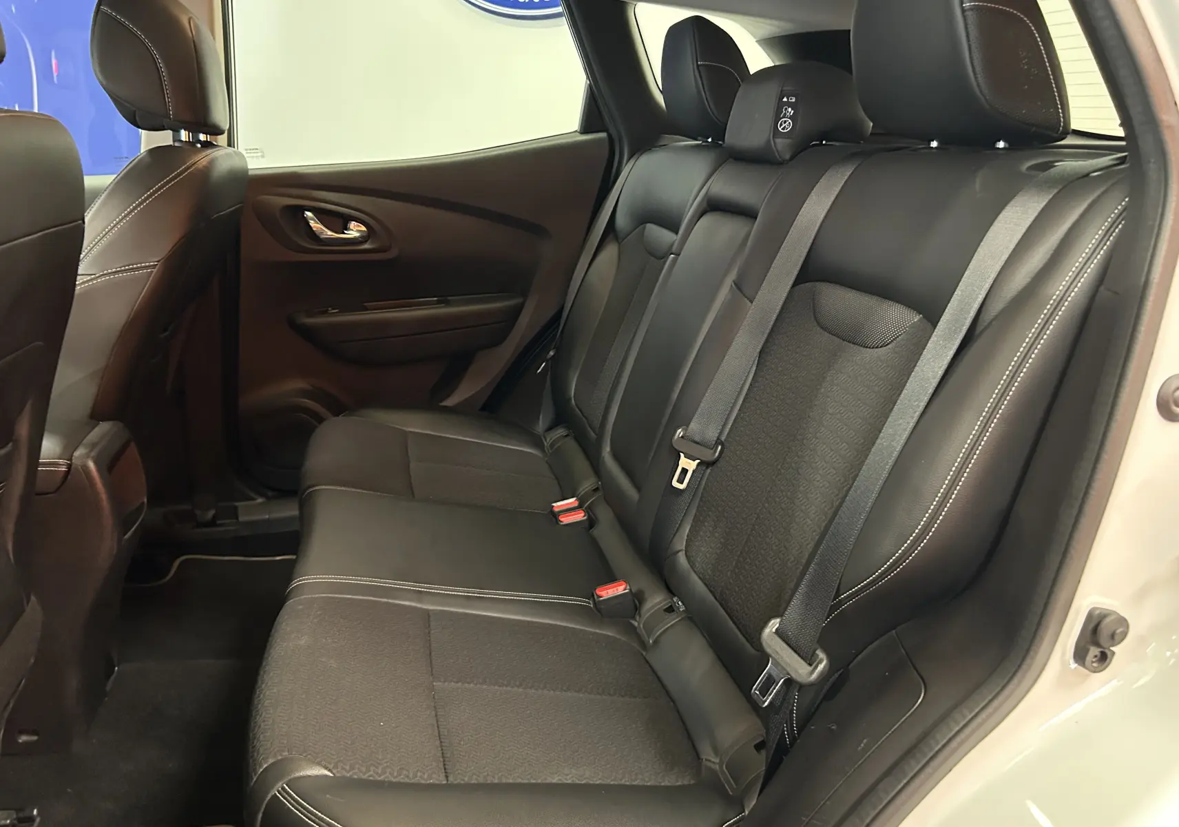 Vue intérieure côté droit des sièges arrière noirs en cuir et tissu du Renault Kadjar blanc, porte ouverte.