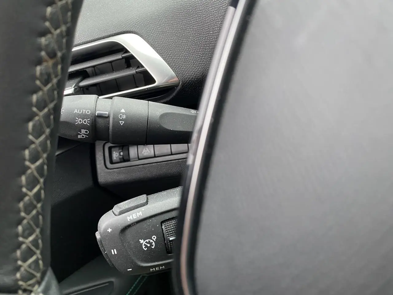Détail du volant et commandes de régulateur de vitesse sur Peugeot 3008 gris platinium, vue intérieure côté conducteur.
