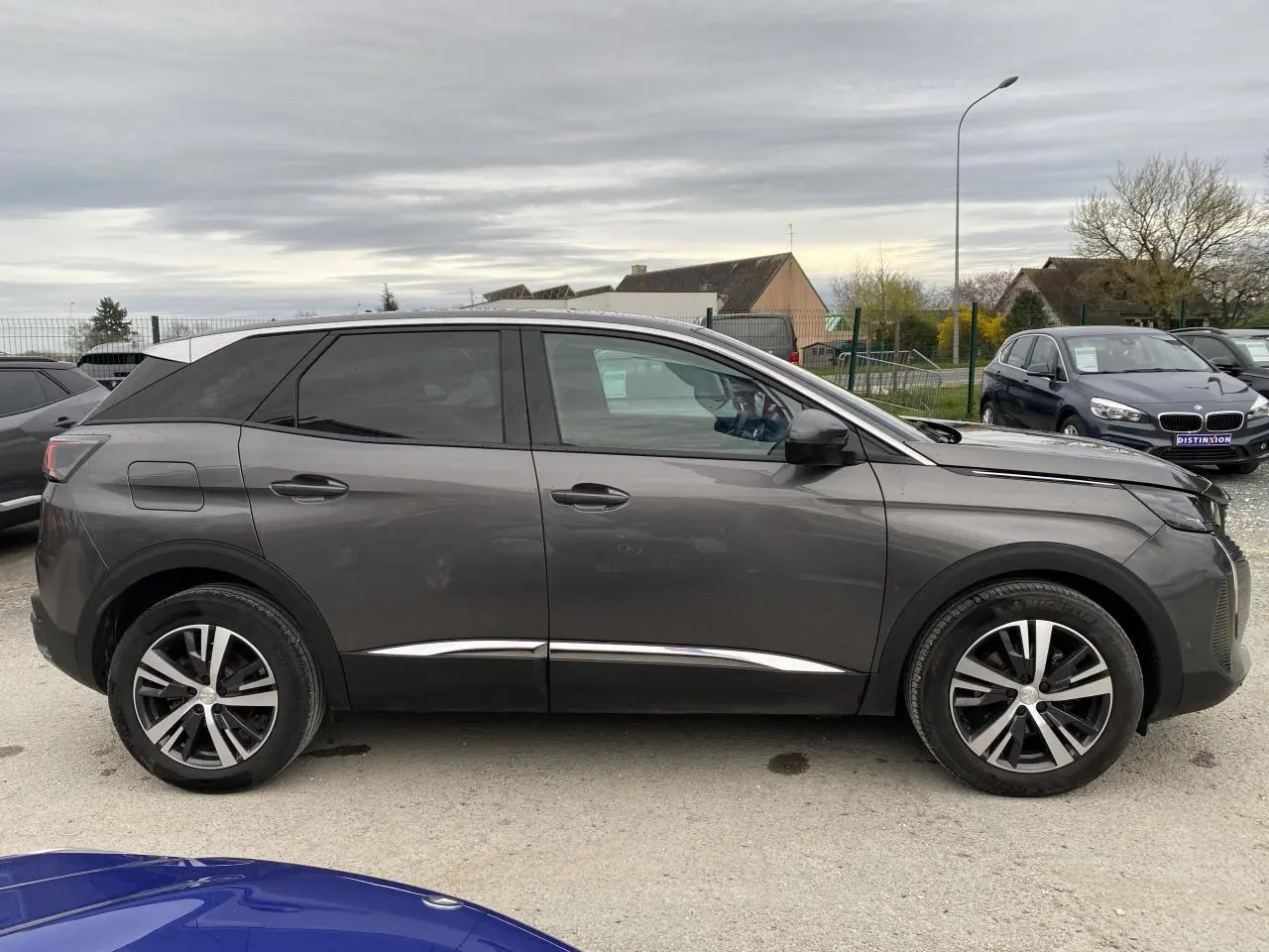 Profil droit d’un Peugeot 3008 gris platinium 2021 avec jantes alliage et vitres teintées, garé en extérieur.