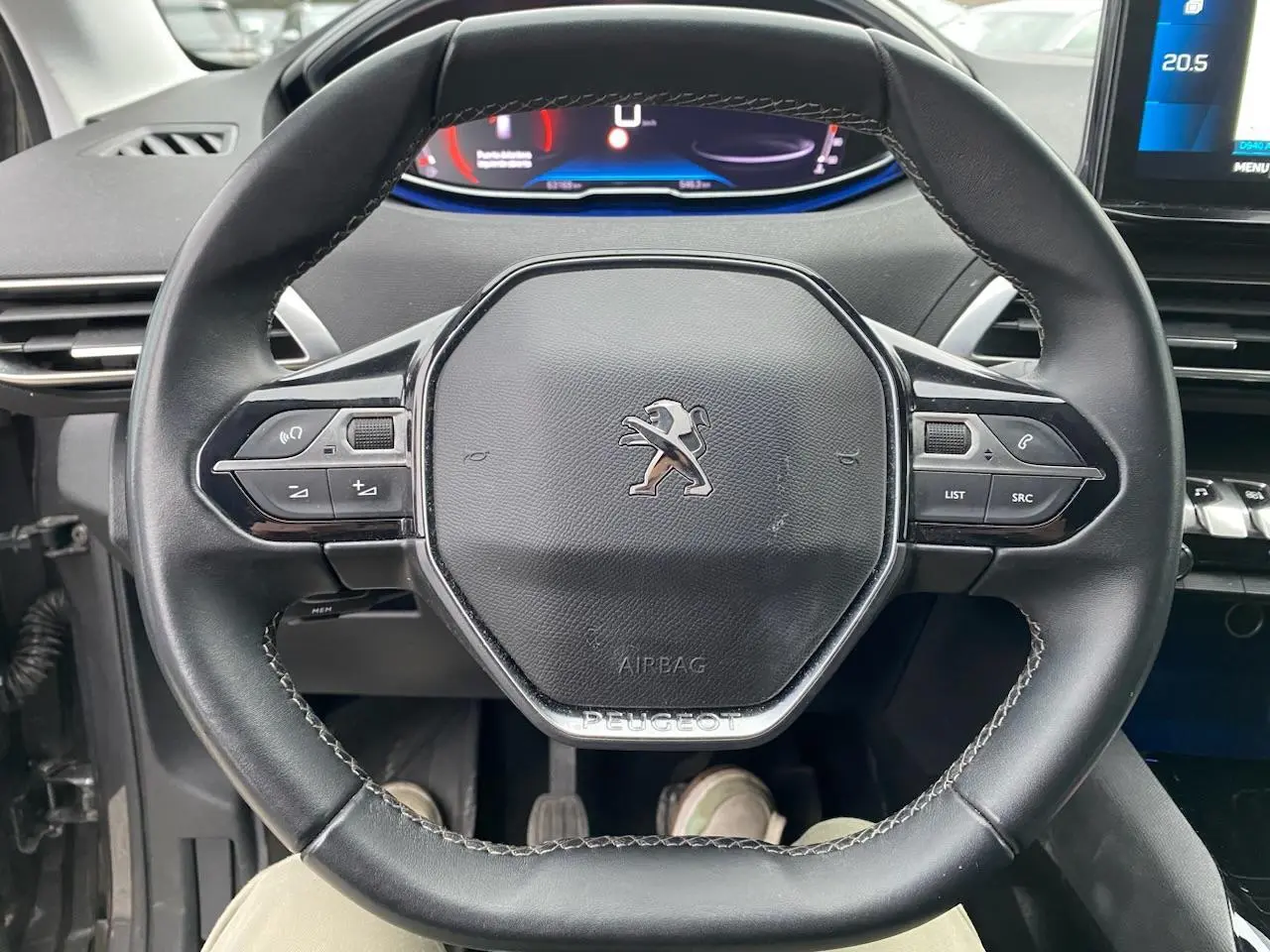 Vue rapprochée du volant compact noir du Peugeot 3008 2021 avec commandes multifonctions et combiné numérique en arrière-plan.