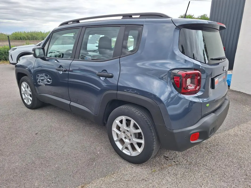 Vue 3/4 arrière droite d’un Jeep Renegade bleu 2024 avec barres de toit et jantes alliage 17 pouces.