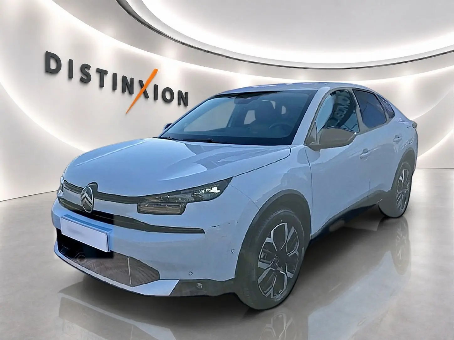 Citroën C4 X blanche vue 3/4 avant droit, avec jantes alu et phares LED dans un showroom lumineux.