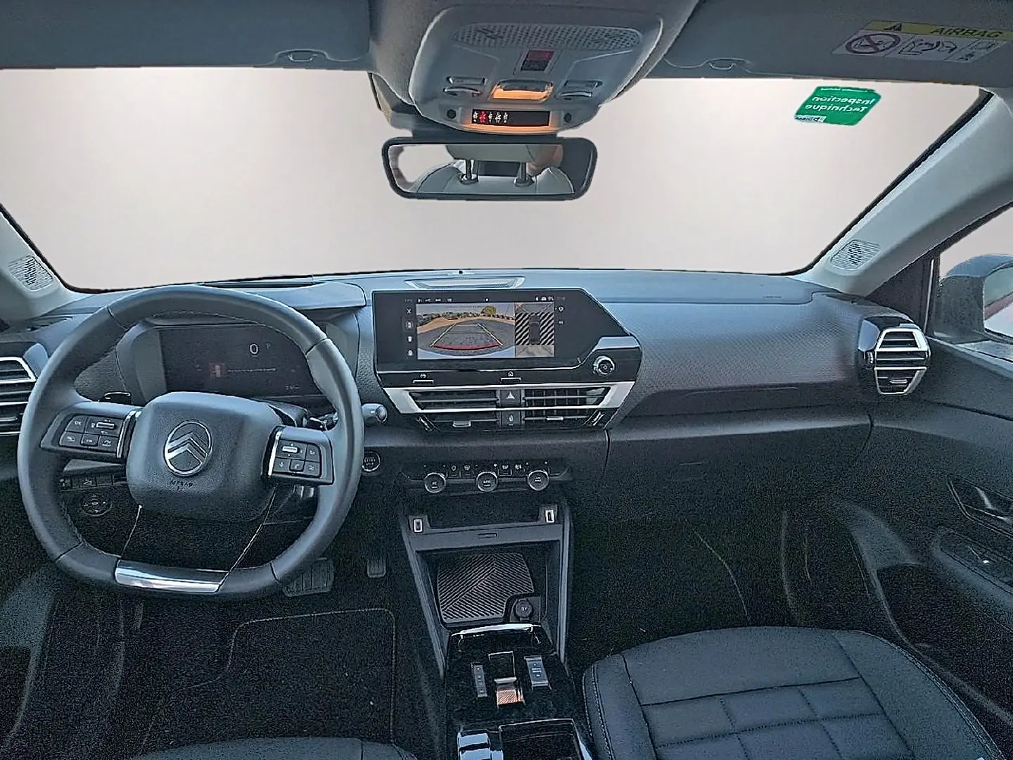 Vue intérieure avant du Citroën C4 X 1.2 hybride 2025, tableau de bord noir avec écran tactile et volant multifonctions.