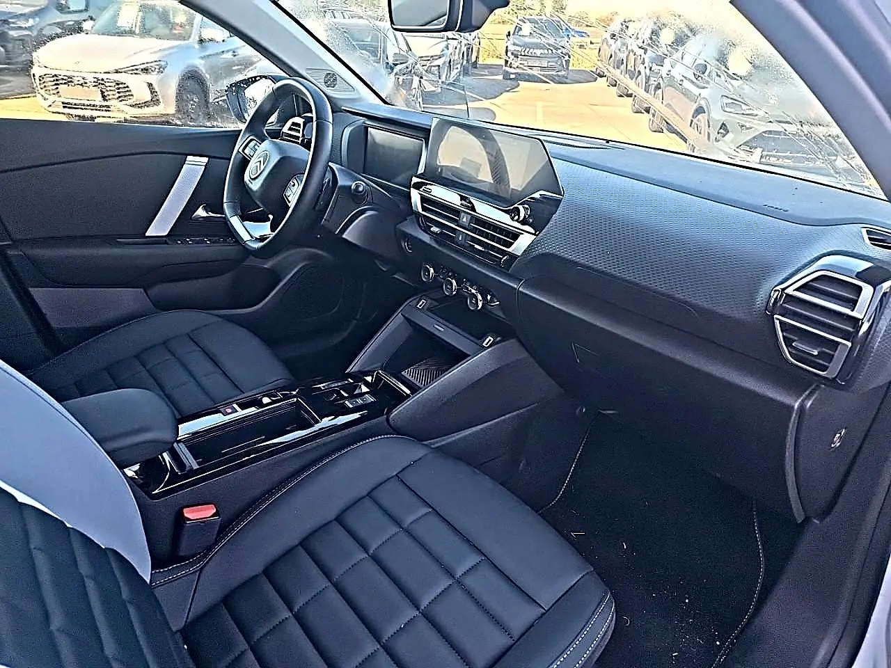 Vue intérieure côté conducteur de la Citroën C4 X 2025, montrant sièges noirs et tableau de bord moderne avec écran tactile.
