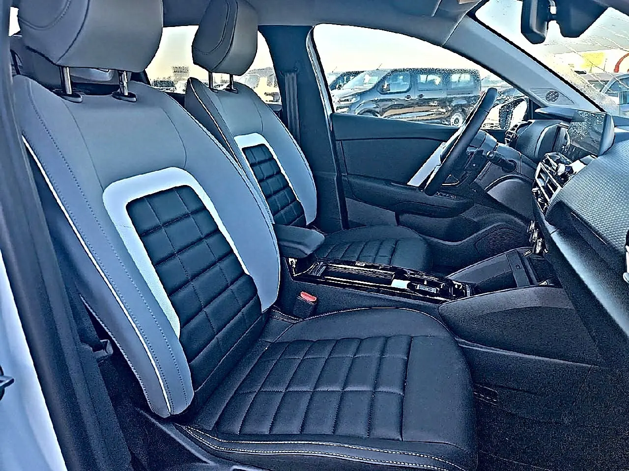Vue intérieure côté droit des sièges avant noirs et gris du Citroën C4 X 2025 avec console centrale moderne.