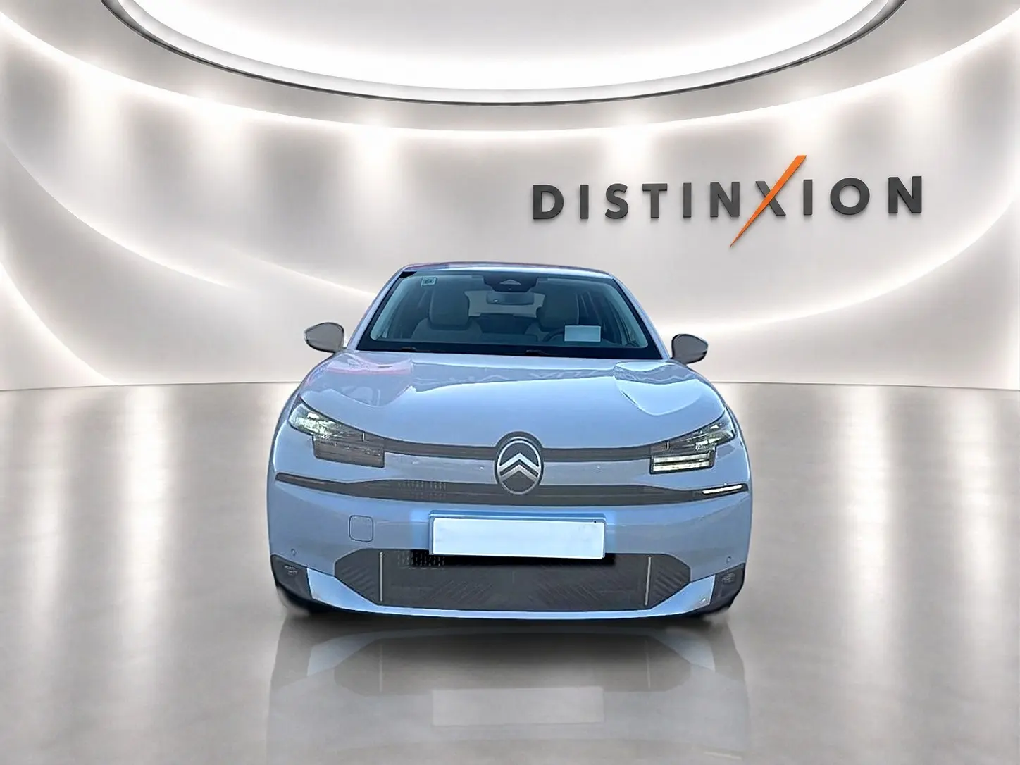 Vue avant d'une Citroën C4 X blanche 2025, avec logo distinctif et éclairage LED moderne dans un showroom lumineux.