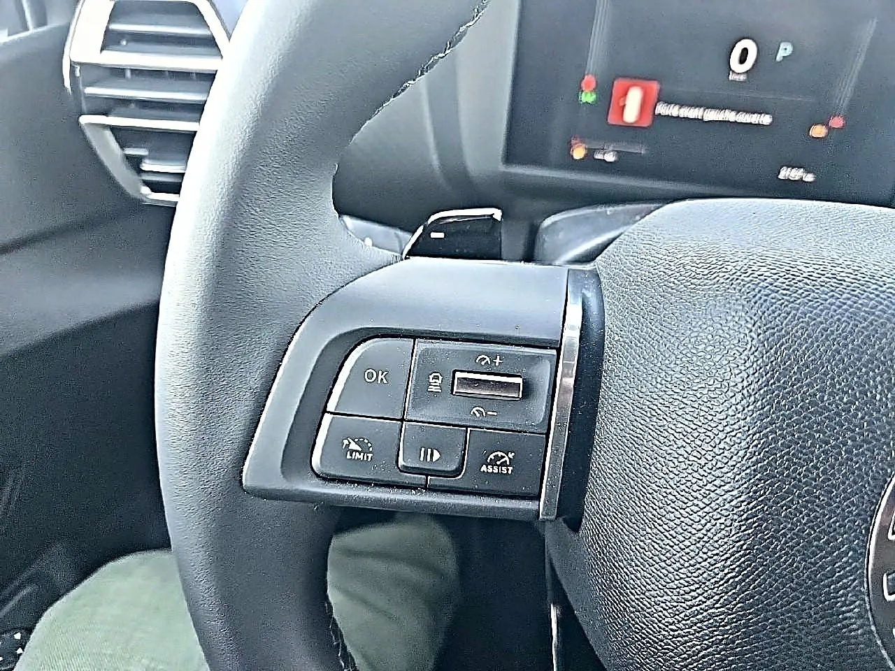 Gros plan sur les commandes au volant cuir noir de la Citroën C4 X blanche, avec écran multifonction en arrière-plan flou.