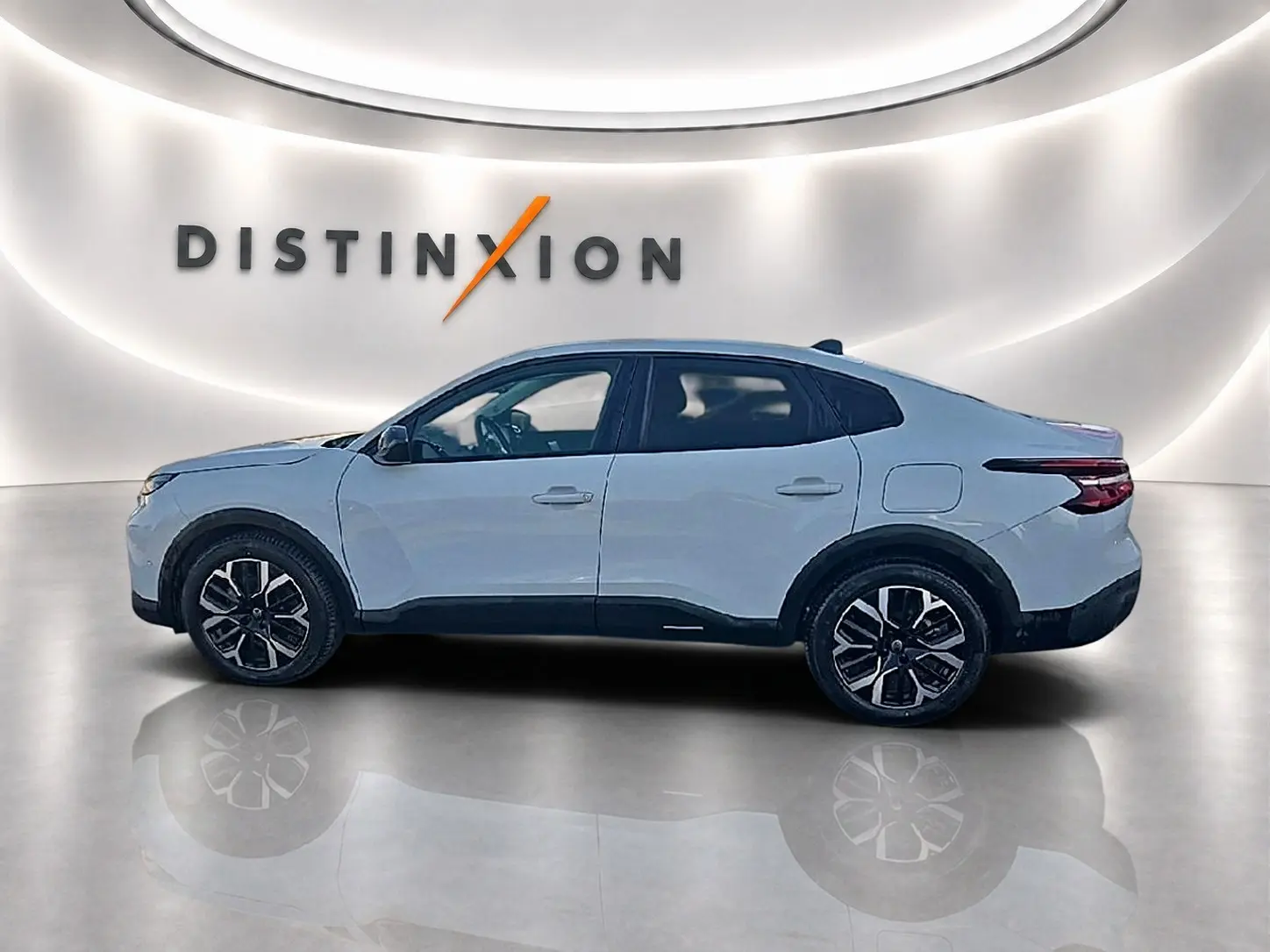 Vue de profil côté gauche d'une Citroën C4 X blanche 2025 avec jantes alu noires et toit noir dans un showroom.