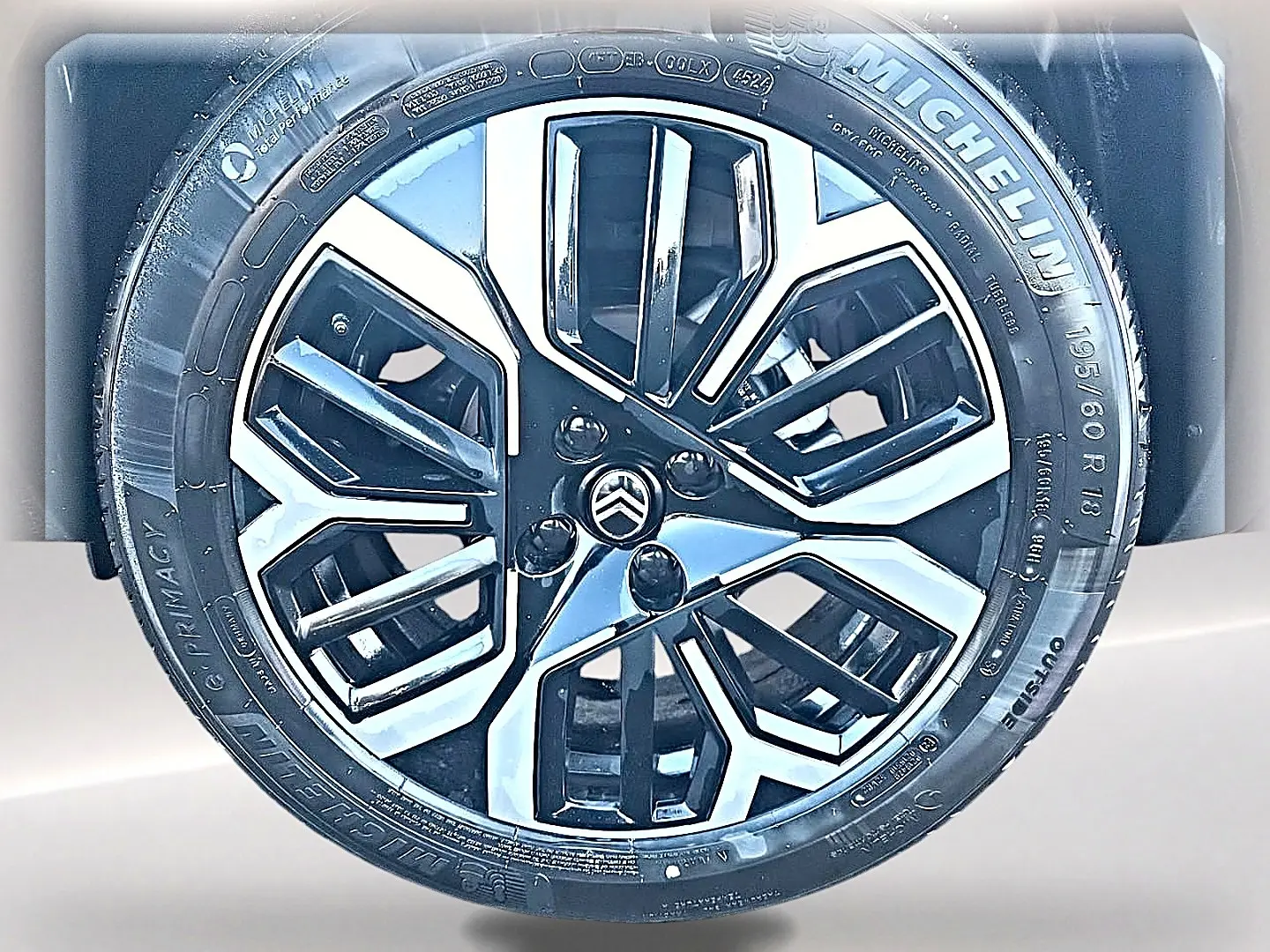Gros plan sur la jante alu noire et argentée avec logo Citroën, montée sur pneu Michelin, carrosserie blanche visible en arrière-plan.