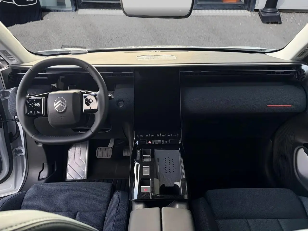 Vue intérieure frontale du tableau de bord noir et volant Citroën du C5 Aircross hybride 2026, sièges tissu bleu.