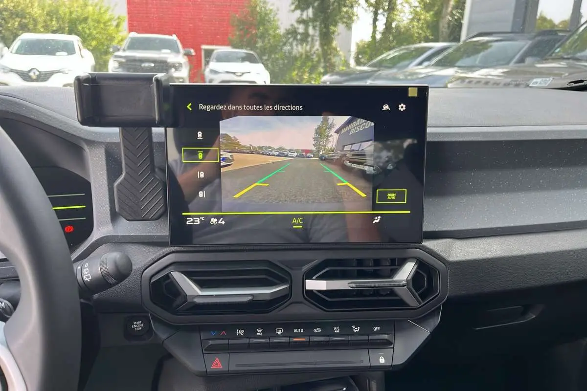 Vue intérieure du tableau de bord du Dacia Duster Hybrid-G 150 4x4, écran central affichant la caméra de recul.