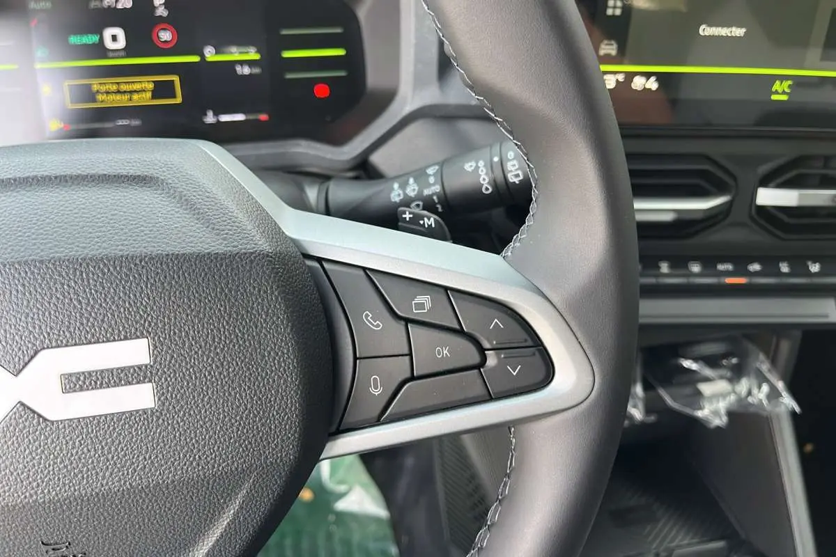 Gros plan sur le volant cuir du Dacia Duster 2026 avec commandes multifonctions et tableau de bord numérique en arrière-plan.